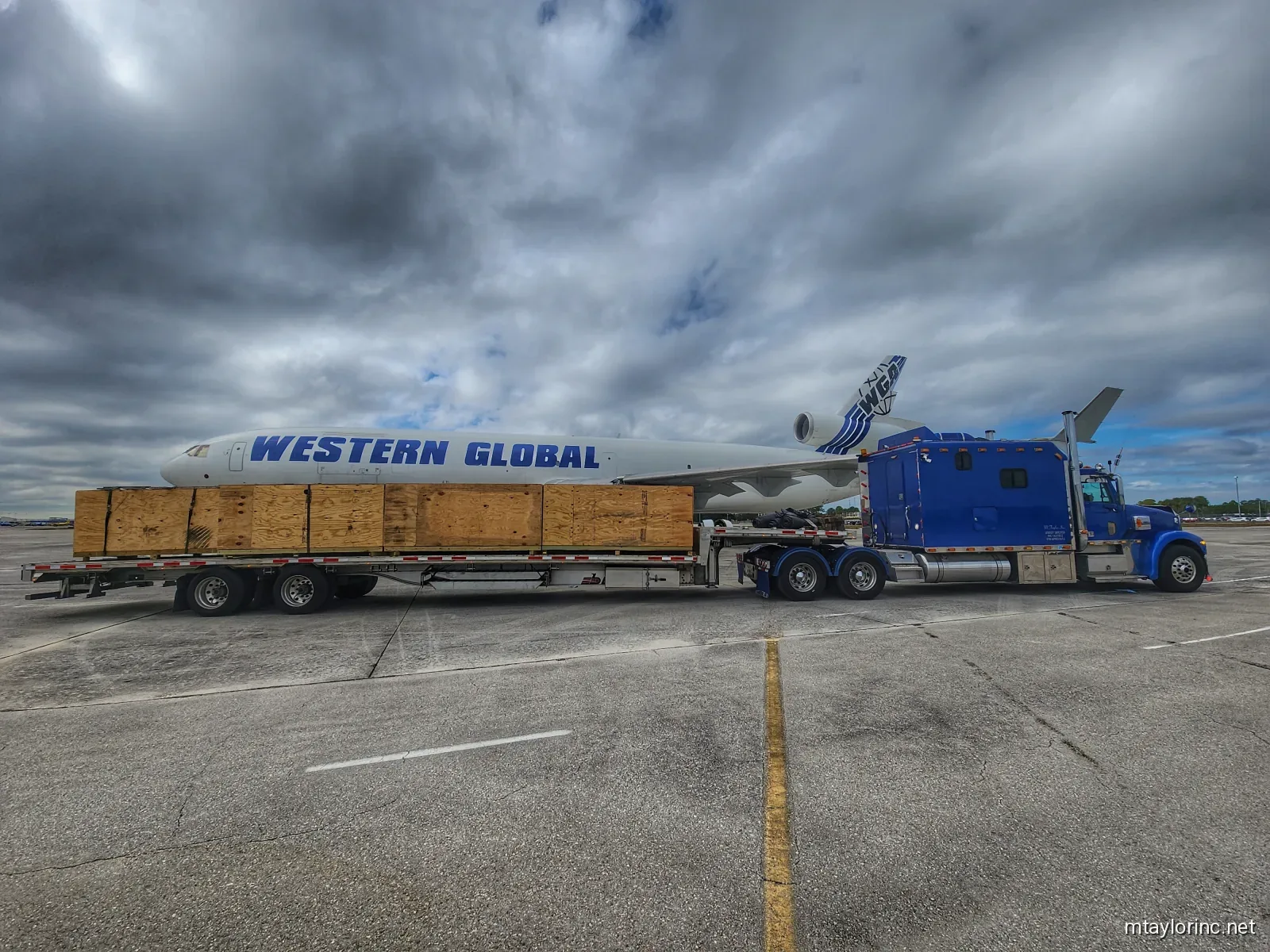 M Taylor Inc stepdeck transporting aircraft parts and Western Global jet engine at airport