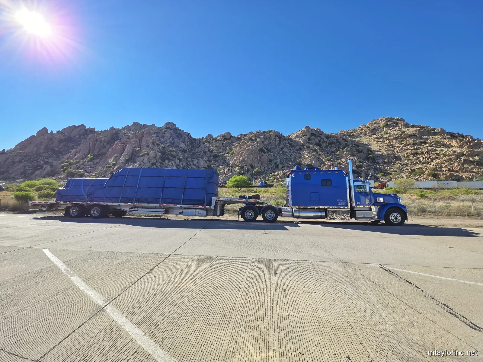 M Taylor Inc stepdeck loaded with construction materials on desert Southwest highway